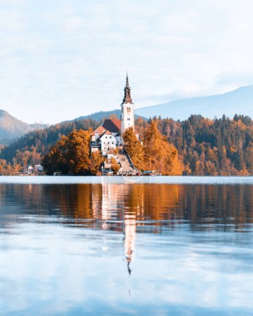 Téléchargez les photos : Vue d'automne colorée sur le lac de Bled dans les Alpes Juliennes, Slovénie. Eglise de pèlerinage de l'Assomption de Marie au premier plan. Photographie de paysage - en image libre de droit