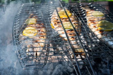 Téléchargez les photos : Griller le poisson dorada sur le gril. Heure d'été dans la cour. Photographie alimentaire - en image libre de droit