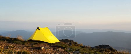 Téléchargez les photos : Vue panoramique sur tente jaune sur fond de paysage montagneux d'automne au lever du soleil matinal. Fond des montagnes - en image libre de droit