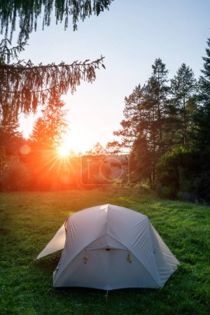 Téléchargez les photos : Tente de touristes sur la prairie verte dans le contexte d'un coucher de soleil incroyable - en image libre de droit