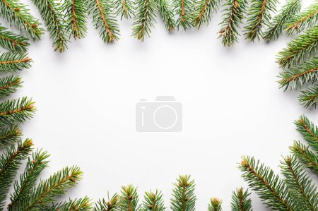 Foto de Fondo creativo navideño con ramitas de abeto sobre fondo de papel de cartón blanco. Plano, vista superior, espacio para copiar - Imagen libre de derechos