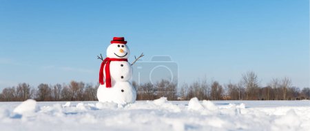 Photo for An amusing snowman, adorned with a trendy red hat and red scarf, graces a snow-covered field with a backdrop of brilliant blue skies. Christmas postcard - Royalty Free Image