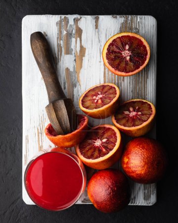 Téléchargez les photos : Oranges siciliennes rouges morceaux et pressoir à main sur planche de bois blanc gros plan. Une alimentation saine concept de vitamine. Photographie alimentaire - en image libre de droit