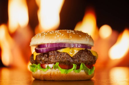 Téléchargez les photos : Cheeseburger frais juteux sur fond de feu de barbecue grill. Burger brûlant. Photographie alimentaire - en image libre de droit