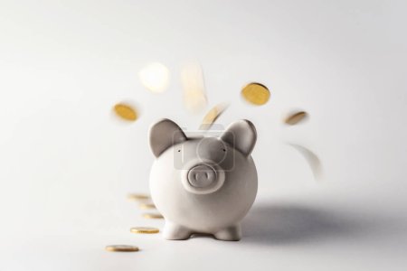 Photo for Gold coins pour into a piggy bank from above. Pig money box with falling golden coins - Royalty Free Image