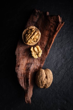 Foto de Nueces enteras y agrietadas con granos en tablero de piedra oscura de cerca. Fotografía alimentaria - Imagen libre de derechos
