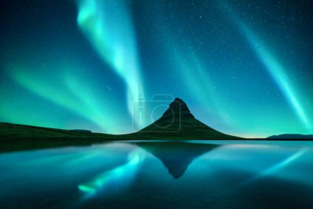 Téléchargez les photos : Reflet de la montagne Kirkjufell et aurores boréales dans le ciel étoilé dans l'eau claire du lac près de la cascade Kirkjufellsfoss en Islande. Paysage nocturne incroyable avec Aurora borealis - en image libre de droit