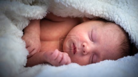 Photo for Portrait of a sleeping newborn boy wrapped in a warm fluffy blanket - Royalty Free Image