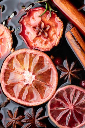 Photo for Mulled wine with slices of dry orange, apple, cinnamon, star anise, rosemary and cranberries close up. Food photography - Royalty Free Image