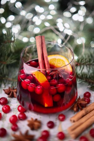 Téléchargez les photos : Vin chaud de Noël en verre avec lumières de Noël et brindilles de sapin sur fond - en image libre de droit