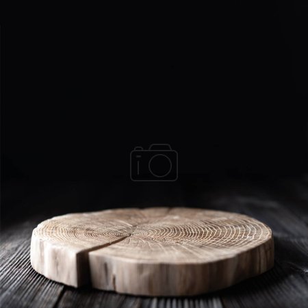 Téléchargez les photos : Assiette en bois sculptée dans un tronc d'arbre sur une vieille table en bois grunge sur fond noir. Peut être utilisé comme support pour votre objet - en image libre de droit