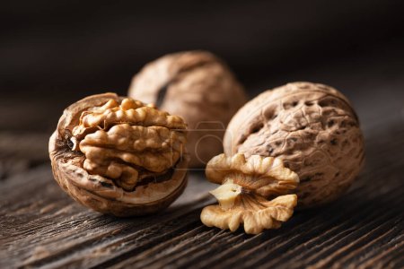 Foto de Nueces enteras y agrietadas con granos en tablón de madera marrón de cerca. Fotografía alimentaria - Imagen libre de derechos