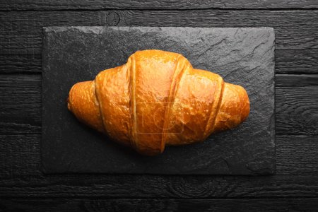 Photo for Freshly baked croissant on a black slate board on a black aged wooden table. Food photography - Royalty Free Image