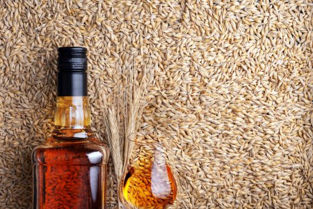 Téléchargez les photos : Un verre de whisky avec bouteille sur grains d'orge comme fond, vue de dessus - en image libre de droit