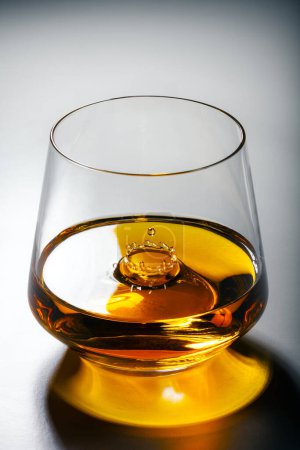 Téléchargez les photos : Un verre de whisky avec une éclaboussure d'une chute à l'intérieur. Concept alcool de luxe - en image libre de droit