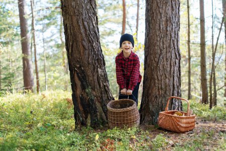 Téléchargez les photos : Petit enfant avec panier ramassant des champignons dans la forêt d'automne. Enfance avec concept amoureux de la nature - en image libre de droit