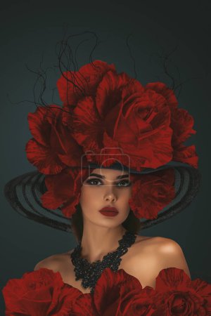 schöne junge Frau mit einem großen Hut, der wunderschön mit großen roten Rosen geschmückt ist. Ein Inbegriff floraler Eleganz und Anmut.