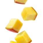Pieces of mango fall on a pile close-up on a white background. Isolated