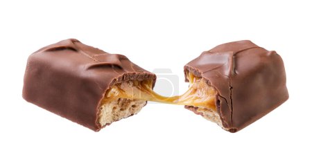 Une barre de chocolat au caramel et aux noix cassées en deux vole en gros plan sur fond blanc. Isolé
