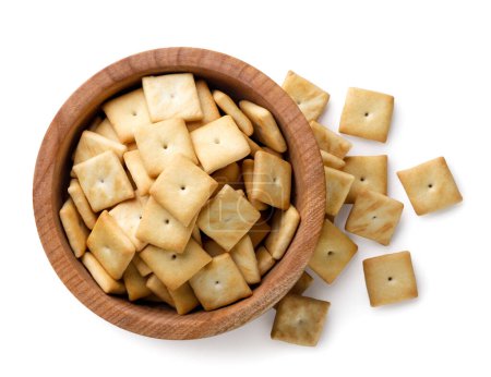 Cracker-Kekse in einem Holzteller und in Großaufnahme auf weißem Hintergrund verstreut. Ansicht von oben