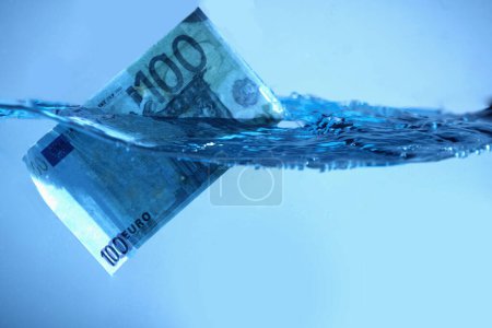 Foto de Crisis financiera global. Billetes en euros hundiéndose en el agua. Copiar espacio. - Imagen libre de derechos