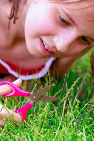 Conceptual image: Obsessive-compulsive disorder (OCD),. Young girl cuts the grass and tries to make it perfectly even. Selective focus.