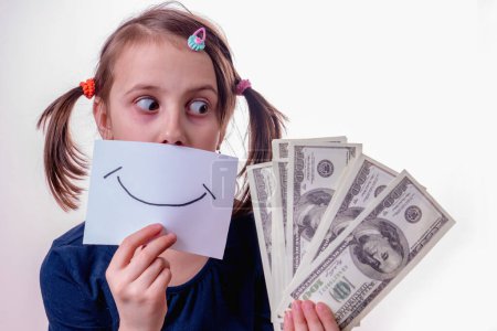 Conceptual image of young girl holding US Dollar money and banner with fake smile as symbol: money can't buy happiness