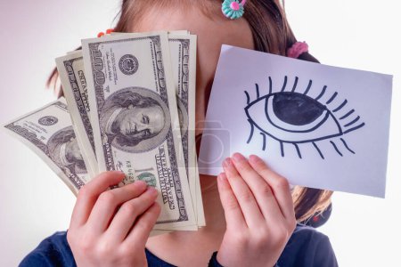 Conceptual image of young girl holding US Dollar money and banner with open eye as symbol: money can buy happiness. Horizontal image.