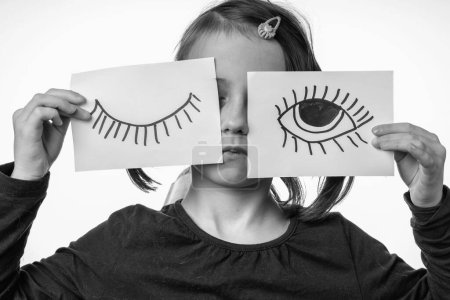 Young girl with painted closed and open eyes as symbol of double standards and cunning. Black and white image.