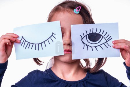 Conceptual photography: double standards. Portrait of young girl is holding a banner with an open eye and a closed eye as a symbol of selective justice.