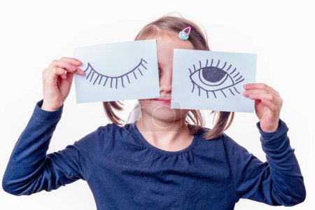 Conceptual photography: double standards. A young girl is holding a banner with an open eye and a closed eye as a symbol of selective justice.