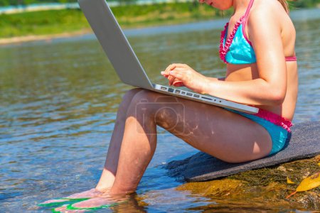 Portrait of young beautiful  girl using and learning with laptop computer while traveling mountains and river. 