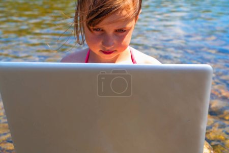 Jeune belle fille utilisant et apprenant avec ordinateur portable tout en voyageant montagnes et rivière. 