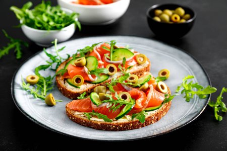 Photo for Toasts with salted salmon, arugula, green olives and cucumber - Royalty Free Image