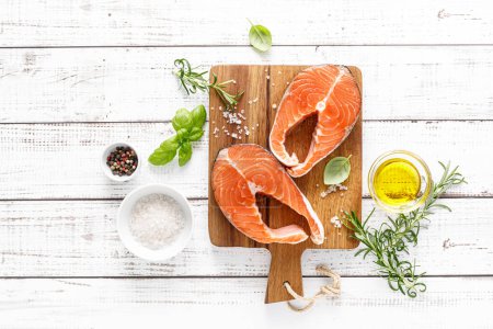 Photo for Fresh raw salmon steaks on a board with ingredients for cooking, top view - Royalty Free Image