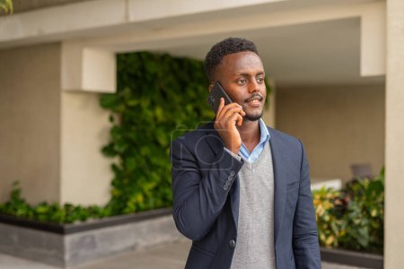 Téléchargez les photos : Portrait d'un bel homme d'affaires africain noir portant un costume et parlant au téléphone - en image libre de droit