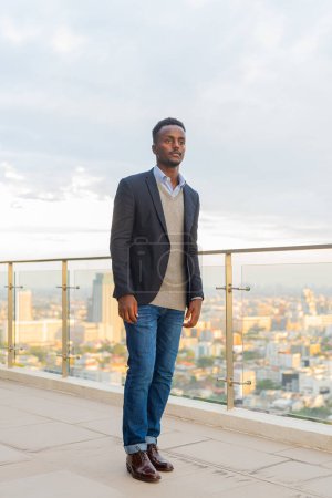 Téléchargez les photos : Portrait d'un bel homme d'affaires africain noir portant un costume pleine longueur tourné - en image libre de droit
