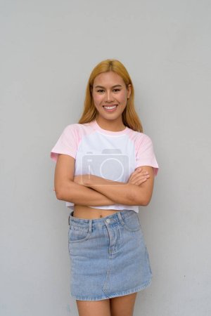 Téléchargez les photos : Portrait de belle fille asiatique heureuse avec des cheveux blonds sur fond uni - en image libre de droit