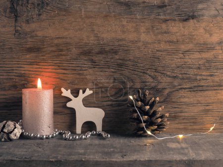Photo for Candle of the first Advent burns, pine cones and Christmas decoration on wood with Christmas lights - Royalty Free Image