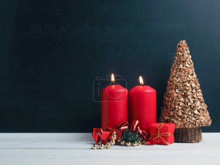 Foto de Velas de Segundo Adviento encendidas con decoración navideña sobre pizarra, fondo estacional o festivo - Imagen libre de derechos