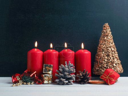 Fourth Advent candles burning with Christmas decoration on a chalkboard, seasonal or holiday background