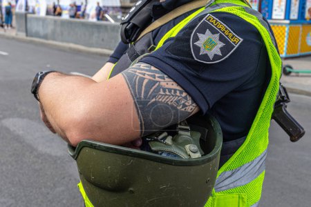 Téléchargez les photos : 24 août : fête de l'indépendance de l'Ukraine. Vue latérale d'un policier ukrainien aux bras croisés, debout sur le fond de la rue centrale. - en image libre de droit