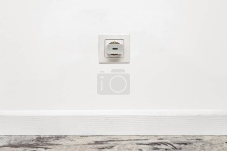Photo for White outlet installed on the white wall with inserted phone adapter, front view. - Royalty Free Image