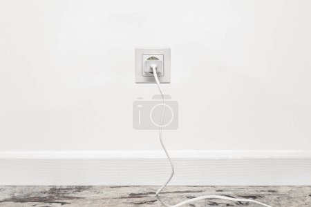 Photo for White outlet installed on the white wall with inserted phone adapter, front view. - Royalty Free Image
