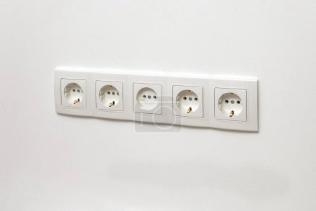 Photo for White five-way wall power socket installed on the white wall, side view. - Royalty Free Image