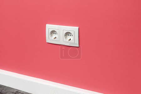 Photo for White double outlet installed on the pink wall, side view. - Royalty Free Image
