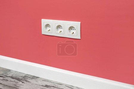 Photo for White triple outlet installed on the pink wall, side view. - Royalty Free Image