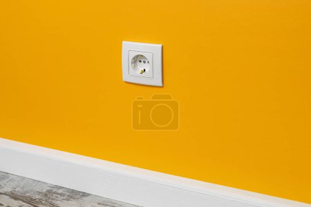 Photo for Yellow outlet installed on the white wall, side view. - Royalty Free Image