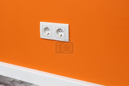 Photo for White double  outlet installed on the orange  wall, side view. - Royalty Free Image