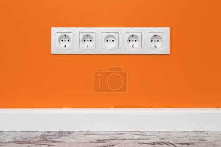 Photo for White five-way wall power socket installed on the pink wall, front view. - Royalty Free Image